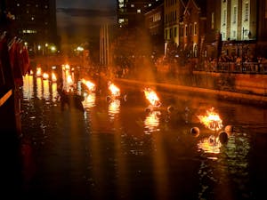 Photograph of burning braziers in a river during WaterFire