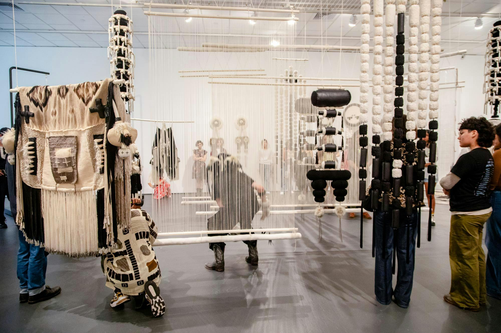 Photograph of people standing and viewing artwork at the Bell Gallery exhibit