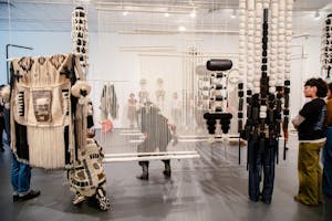 Photograph of people standing and viewing artwork at the Bell Gallery exhibit