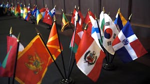 A collection of mini national flags line a dark floor.