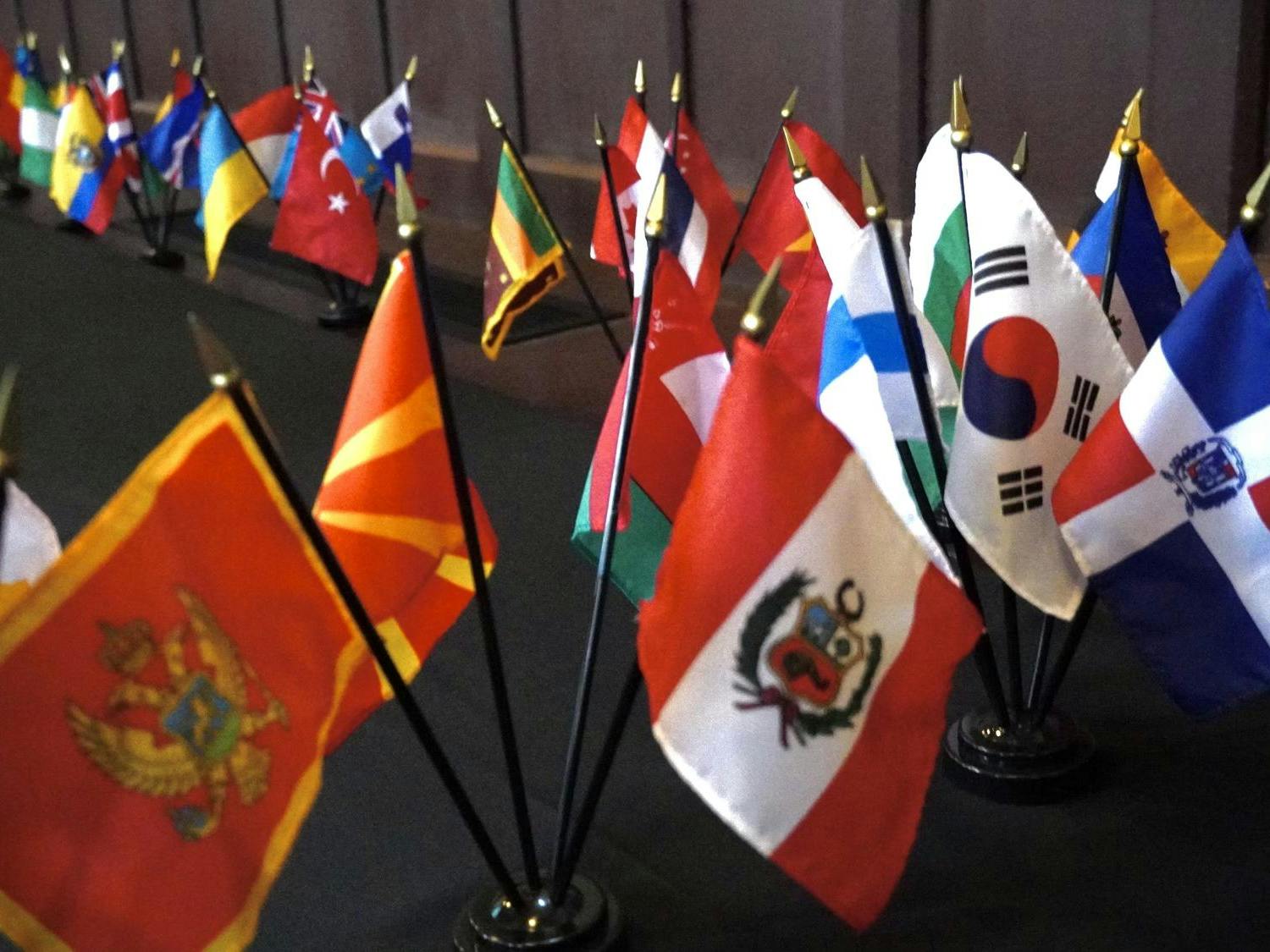 A collection of mini national flags line a dark floor.