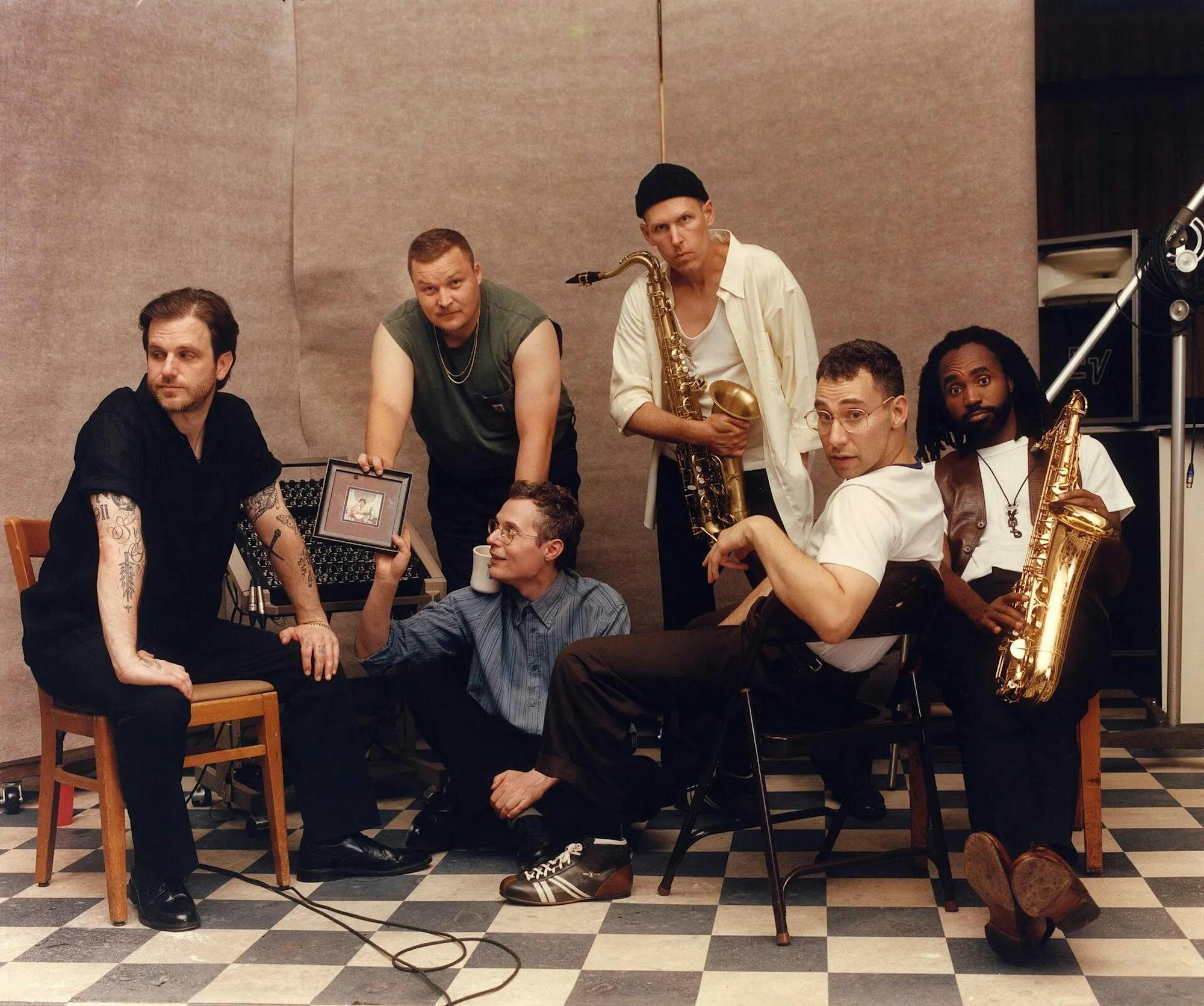 Members of the band Bleachers posing for a photo with each member holding up their respective instruments.