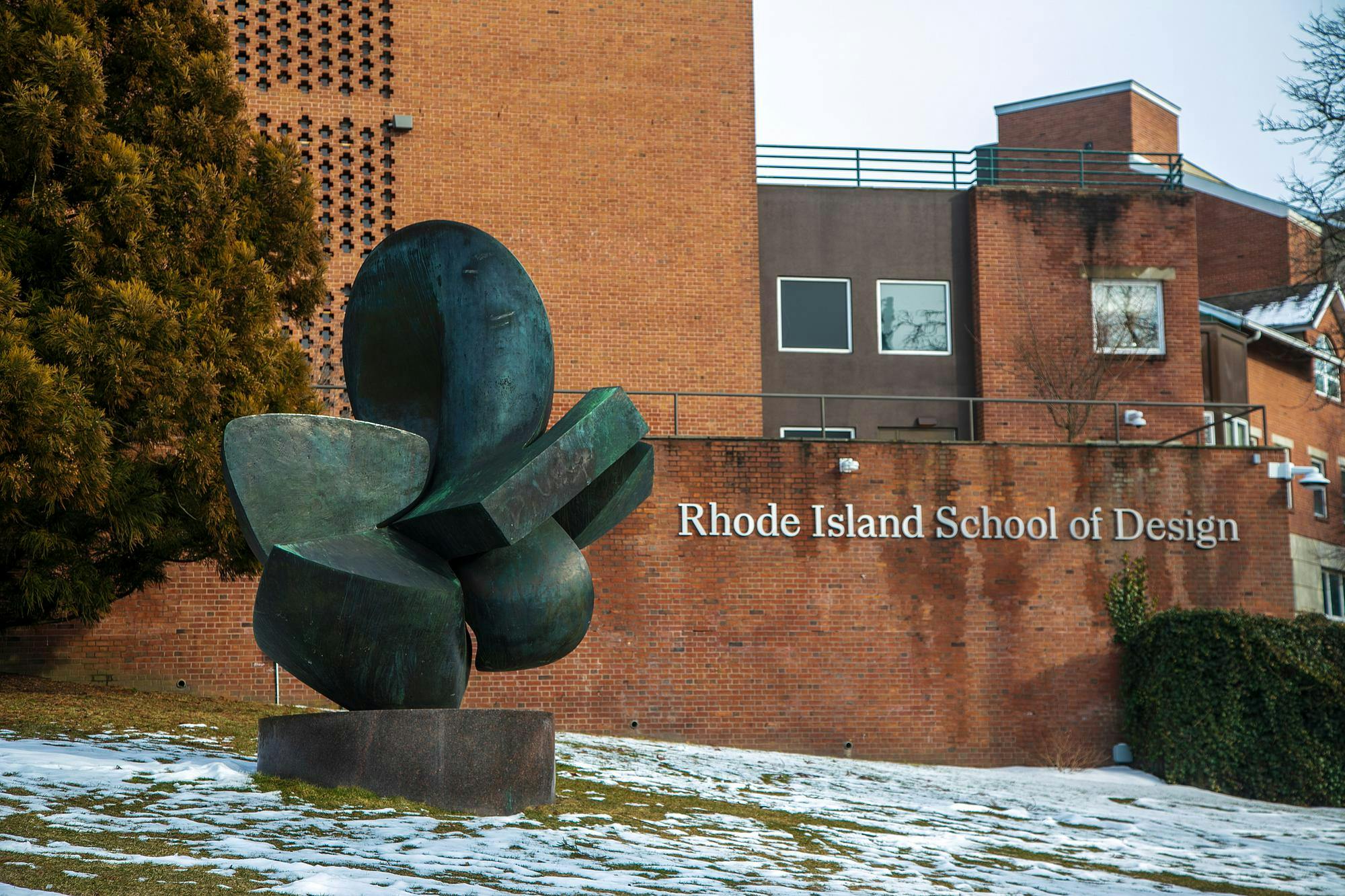 A view of a Rhode Island School of Design building from Benefit Street. In front of the brick building, there is a green statue. 