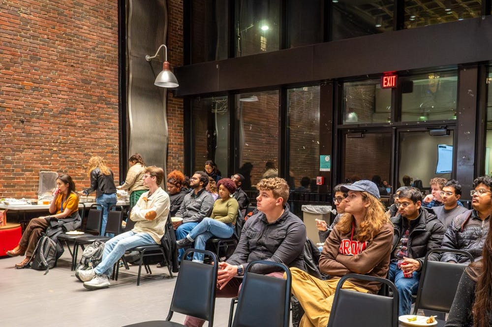 Photo of the GSC meeting where a crowd of students look up at the speaker.