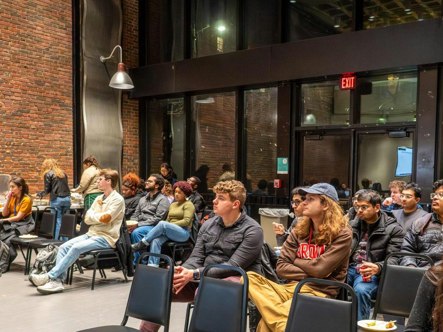 Photo of the GSC meeting where a crowd of students look up at the speaker.