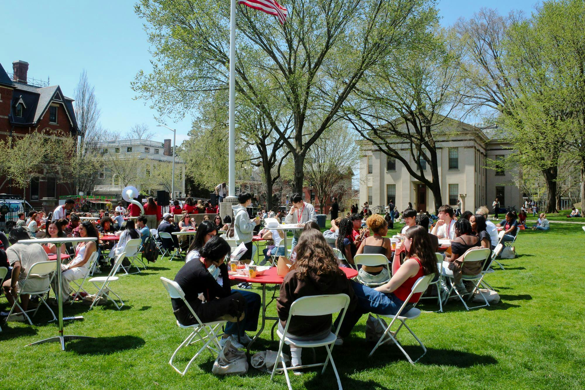 Students sit at circular red tables on the Main Green.