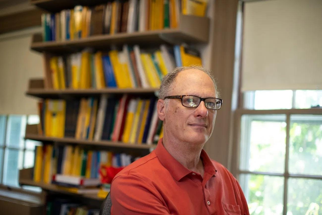 Joseph Silverman posing in front of a shelf of books. 

