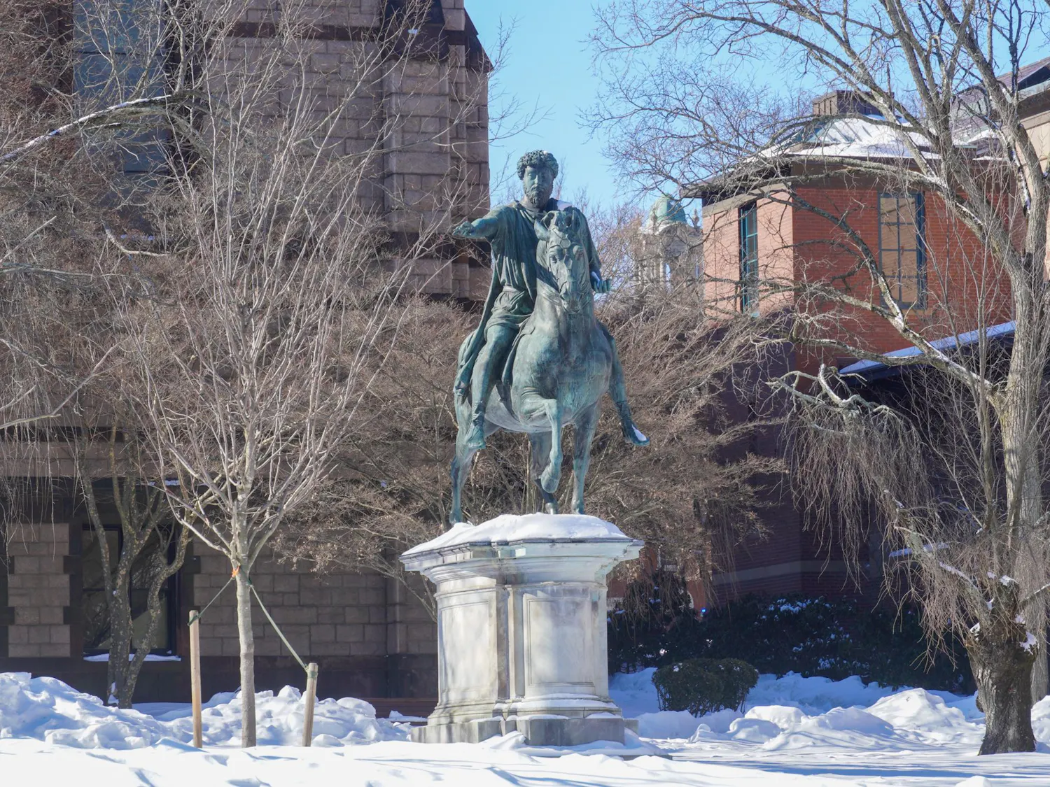 Photo of the Marcus Aurelius statue atop of the hill on Ruth J. Simmons Quadrangle with a layer of snow on the ground.