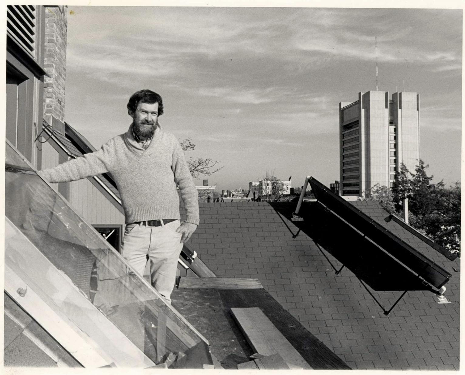 A black and white photo of a man standing on the roof of a building in front of the Sciences Library. 