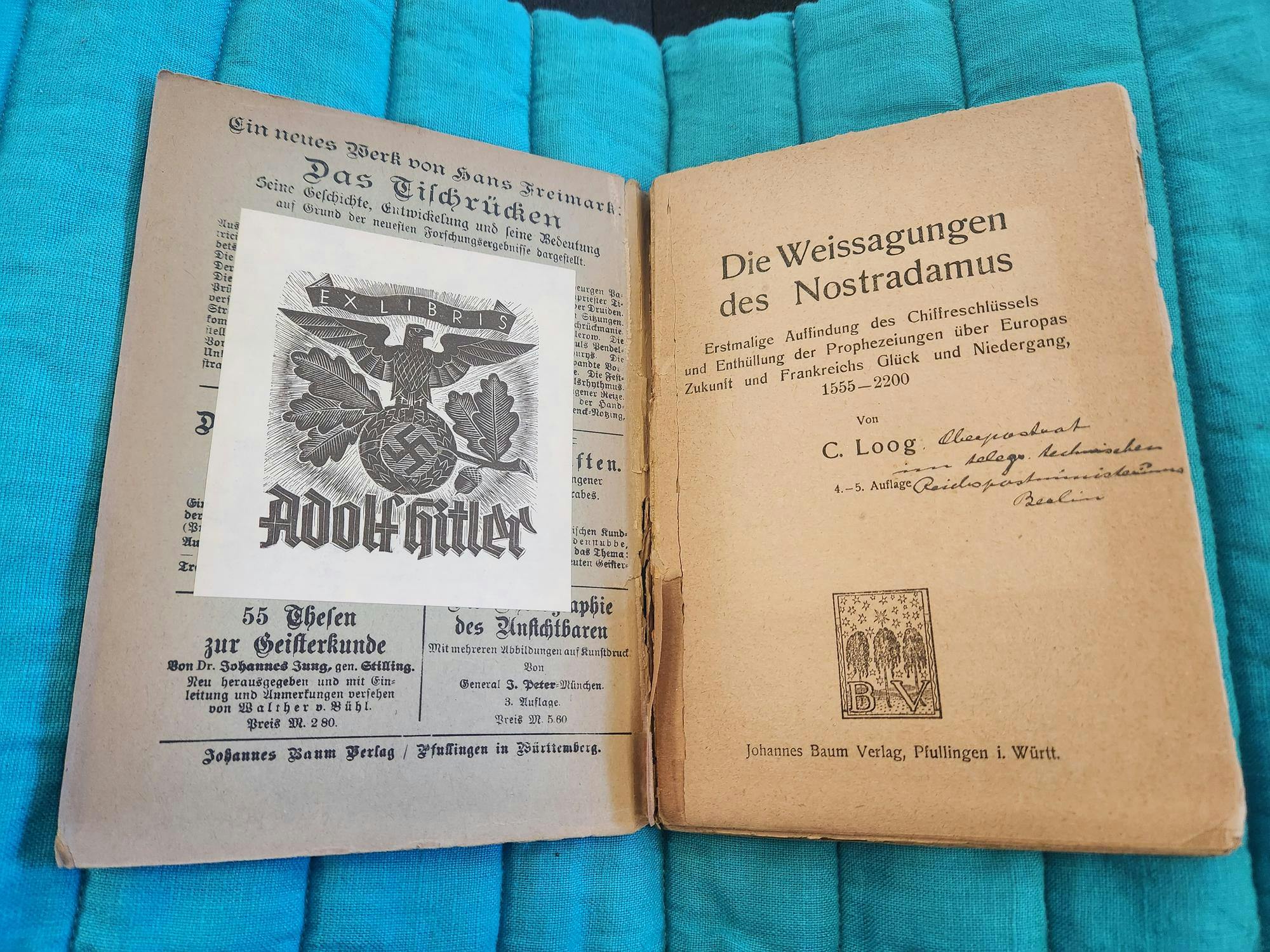 An open title page to "The Prophecies of Nostradamus," with handwritten lettering under the words "Die Weissagungen des Nostradamus." On the left page, there is a paper attachment that states "Ex Libris Adolf Hitler" with Nazi party symbolism and a swastika.