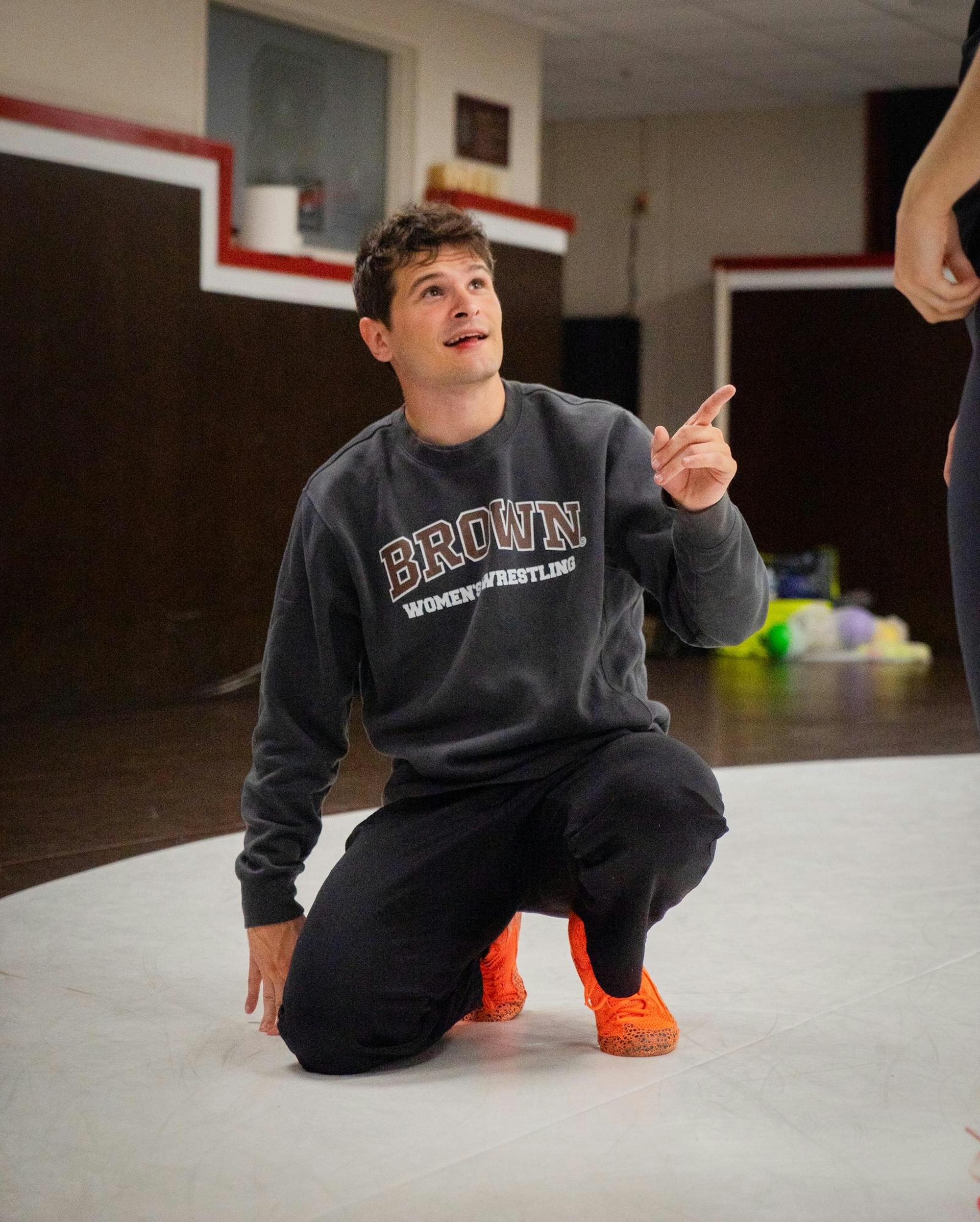 Head Coach Nick Lattanze '21 crouching and pointing at a wrestler