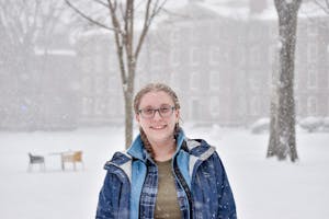 A photo of a girl with two blonde braids standing in the snow.