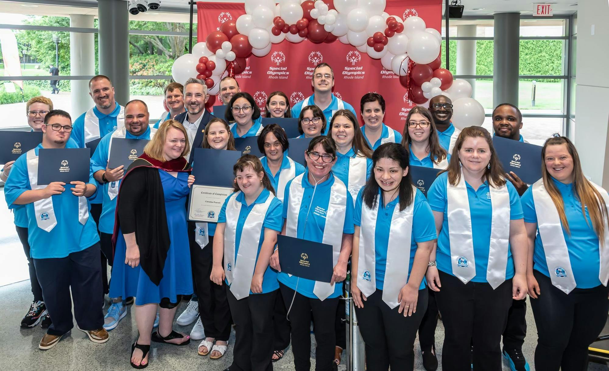 A group of graduates pose with their stoles and diplomas.