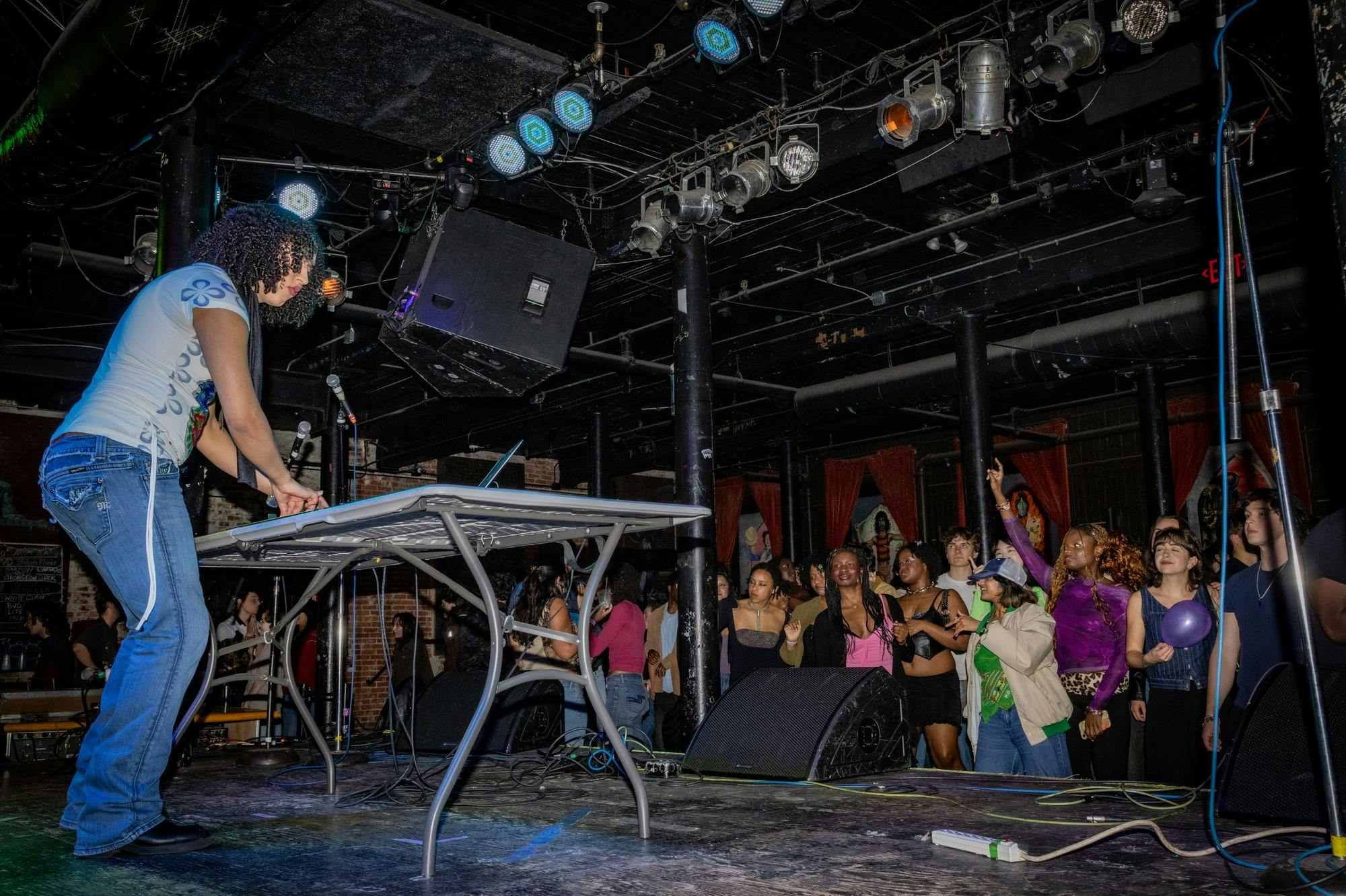A DJ plays a set on stage in front of a dancing crowd.