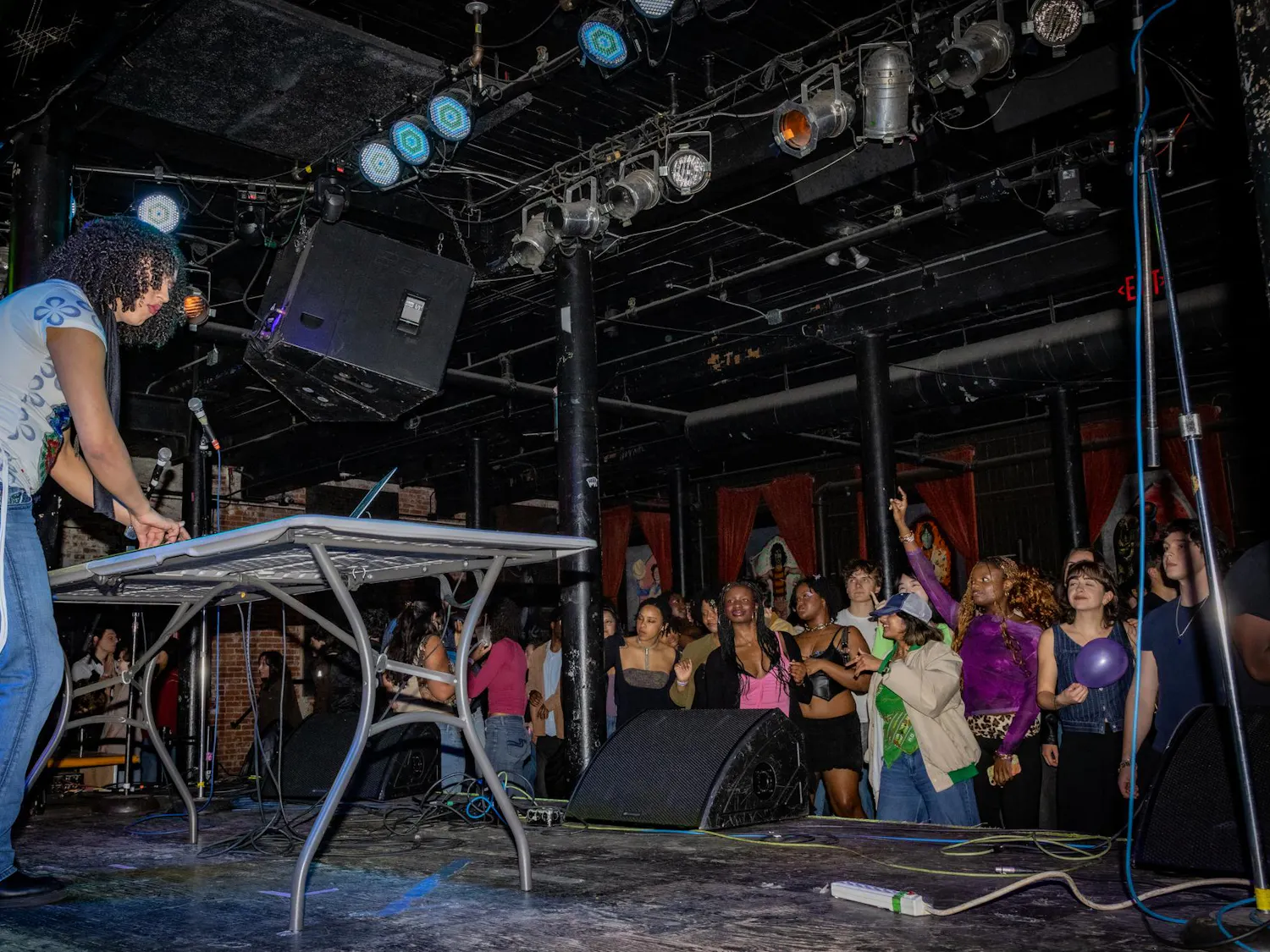 A DJ plays a set on stage in front of a dancing crowd.