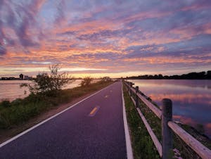 A running path runs through a small lake during an evening sunset.