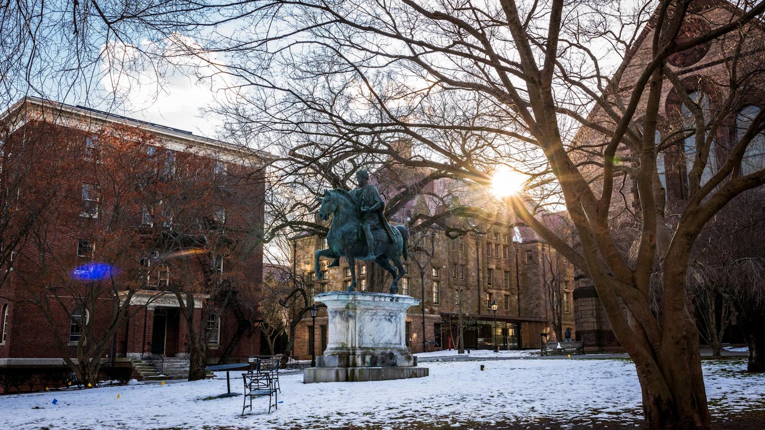 Statue of Marcus Aurelius in the middle of Brown’s snowy campus as the setting sun shines through the surrounding buildings.