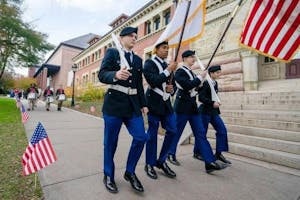Military officers walk in line outside of Lyman Hall.