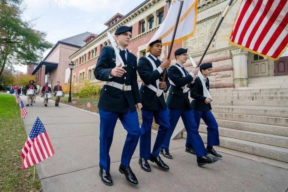 Military officers walk in line outside of Lyman Hall.