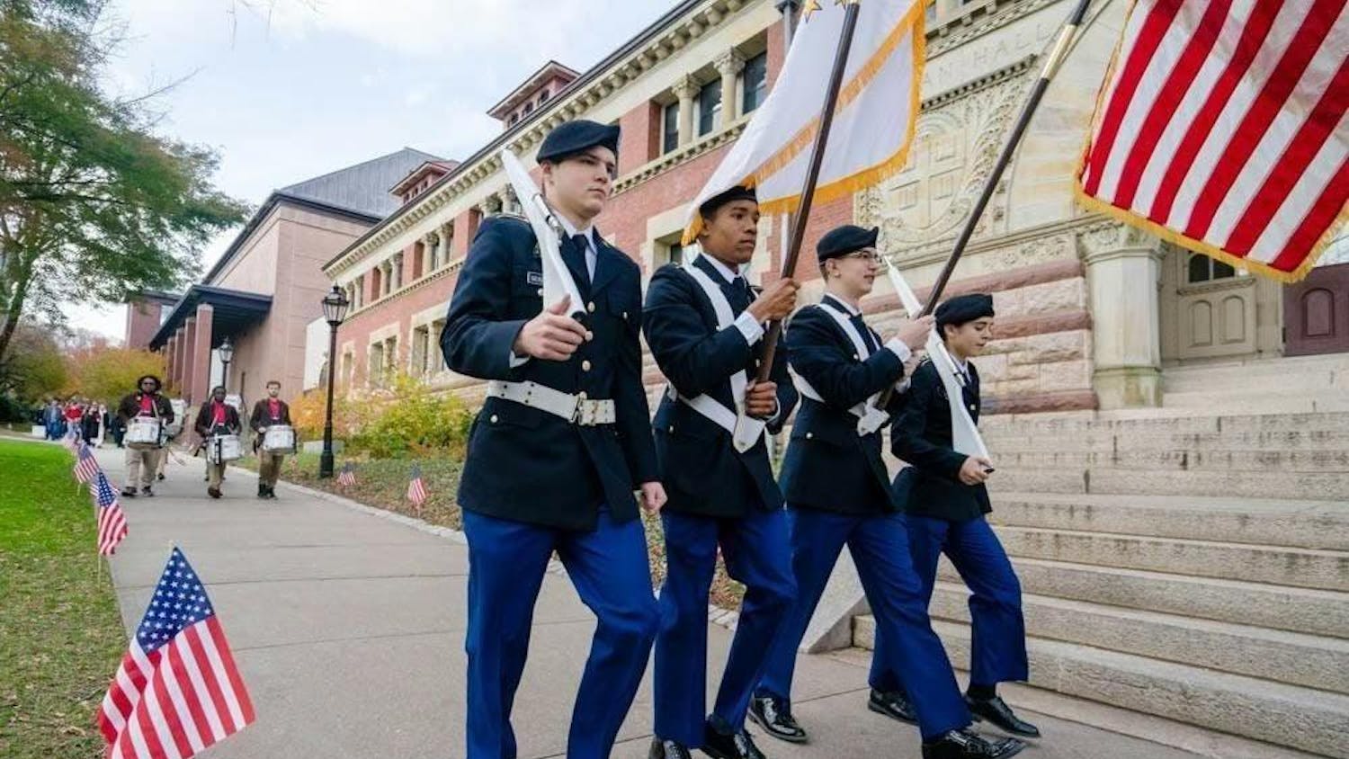 Military officers walk in line outside of Lyman Hall.