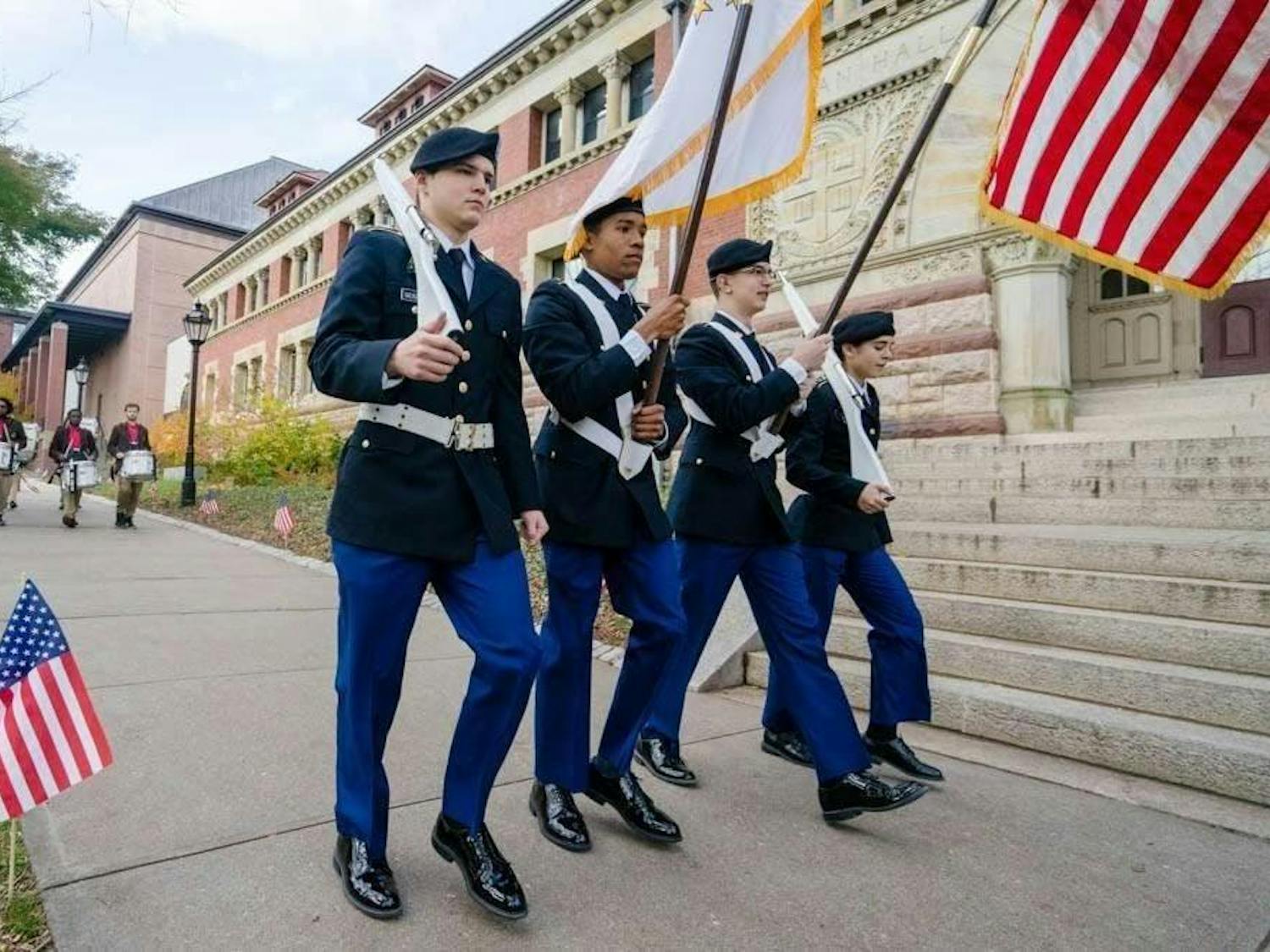 Military officers walk in line outside of Lyman Hall.