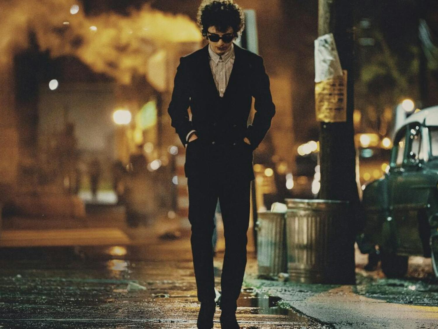 An image of Timothée Chalamet with sunglasses walking through a wet street.
