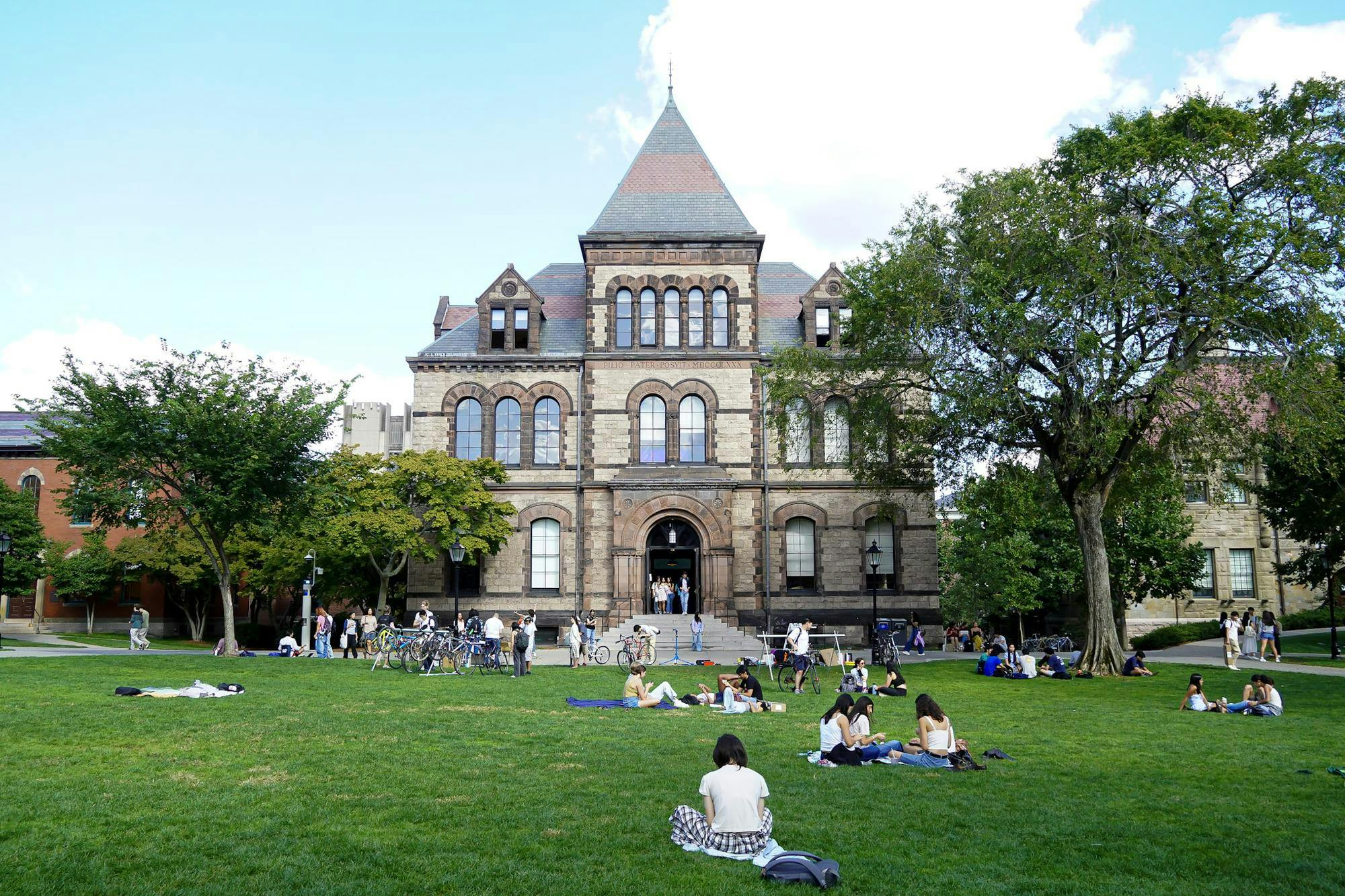 Photo of Sayles Hall with students relaxing on the Main Green.
