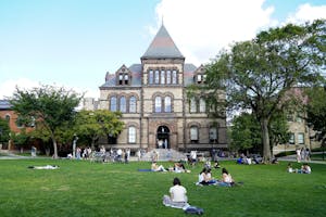 Photo of Sayles Hall with students relaxing on the Main Green.