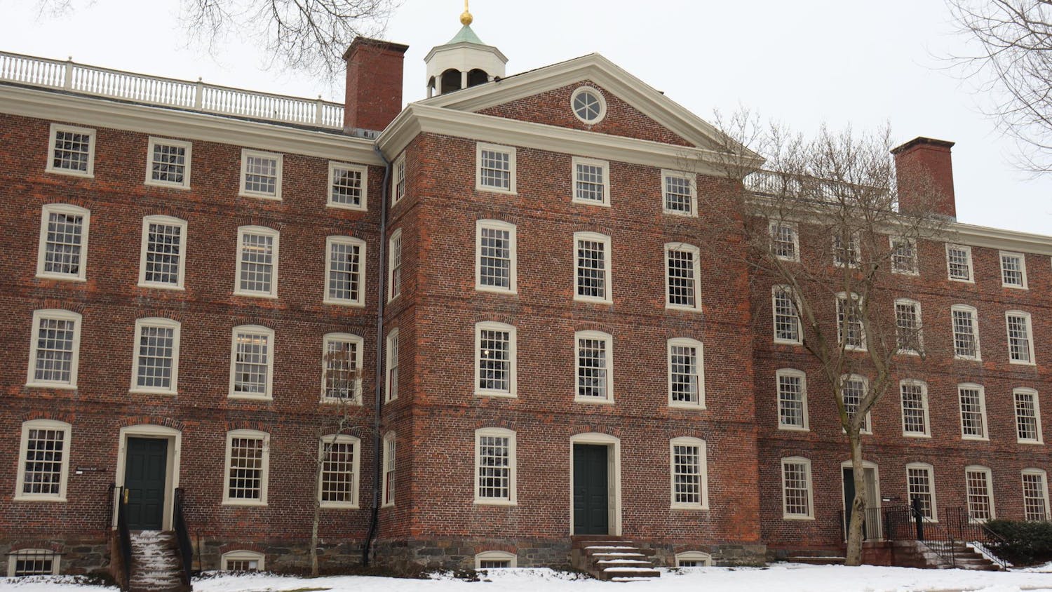 University Hall in the winter with multiple bare trees and snow in the front.