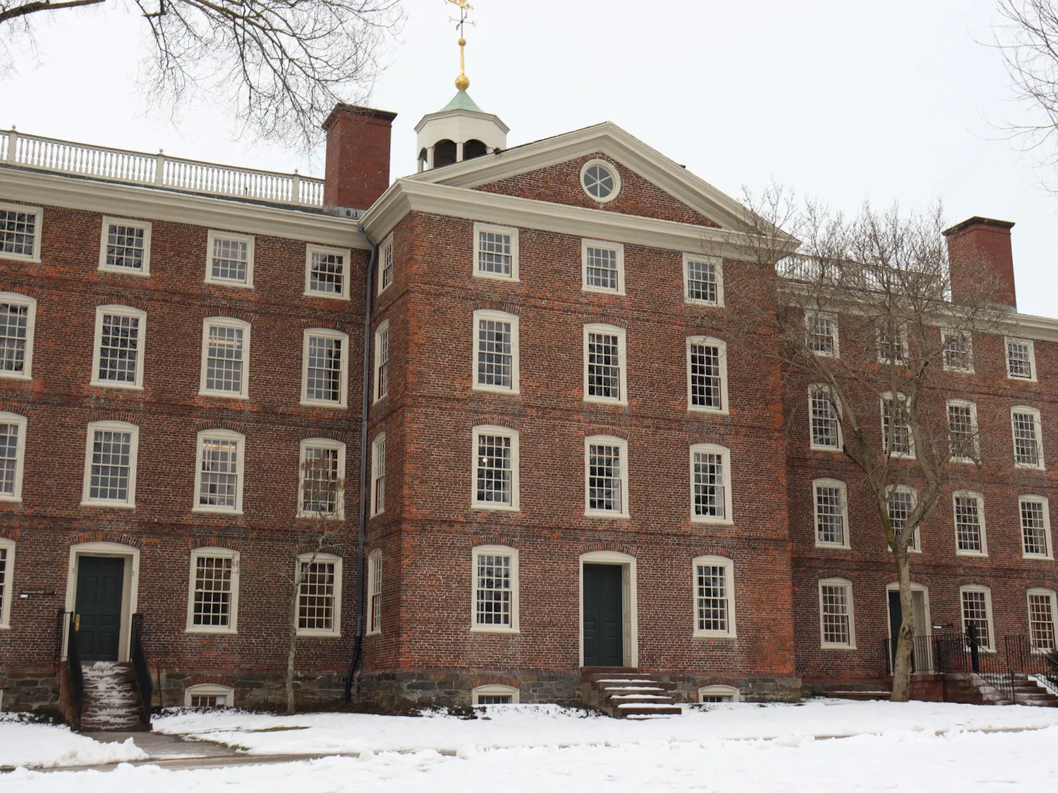 University Hall in the winter with multiple bare trees and snow in the front.