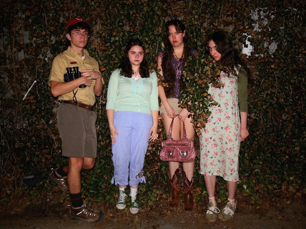 Image of four actors from Something on the Green’s student theatre company standing against a wall of leaves.