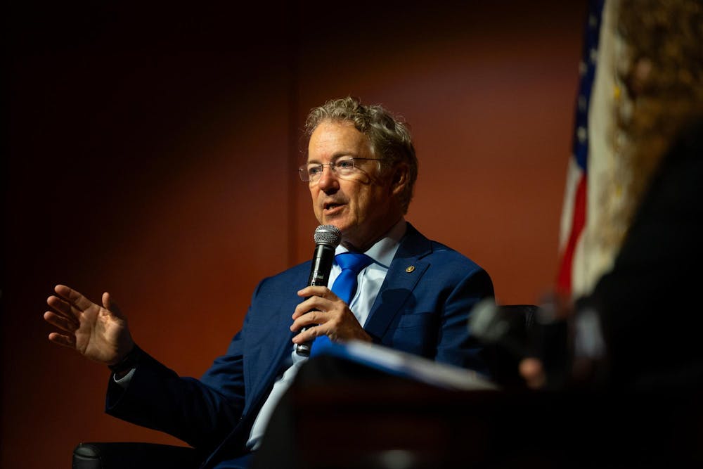 U.S. Sen. Rand Paul, a gray-haired man with glasses and a navy blue suit, solemnly speaks into a microphone onstage.