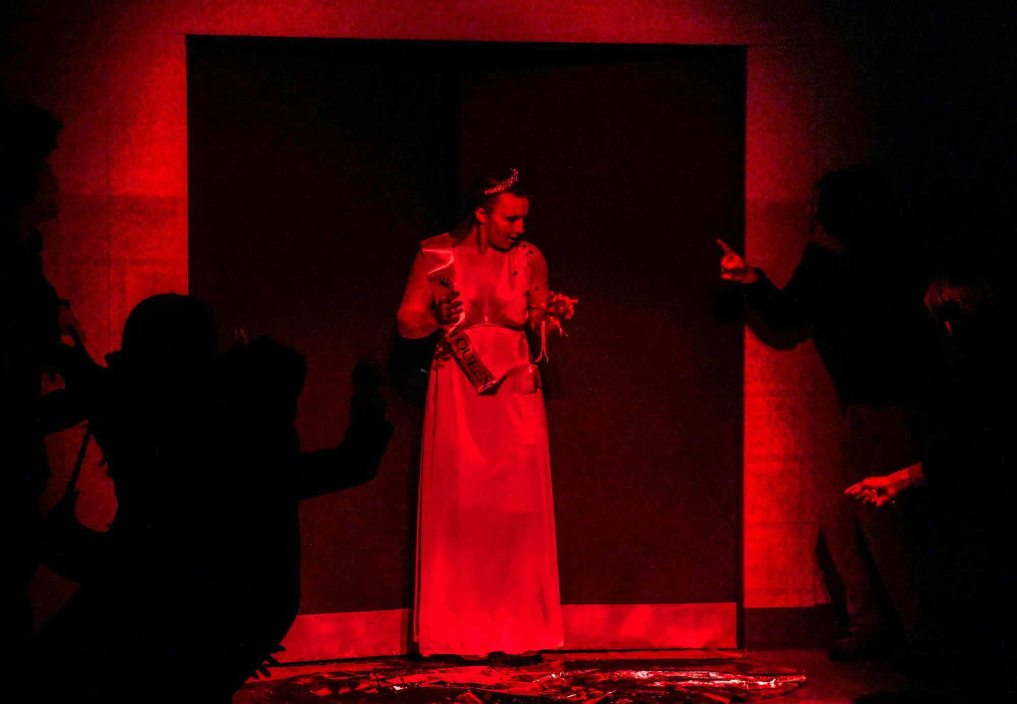 A young lay stands in red light.