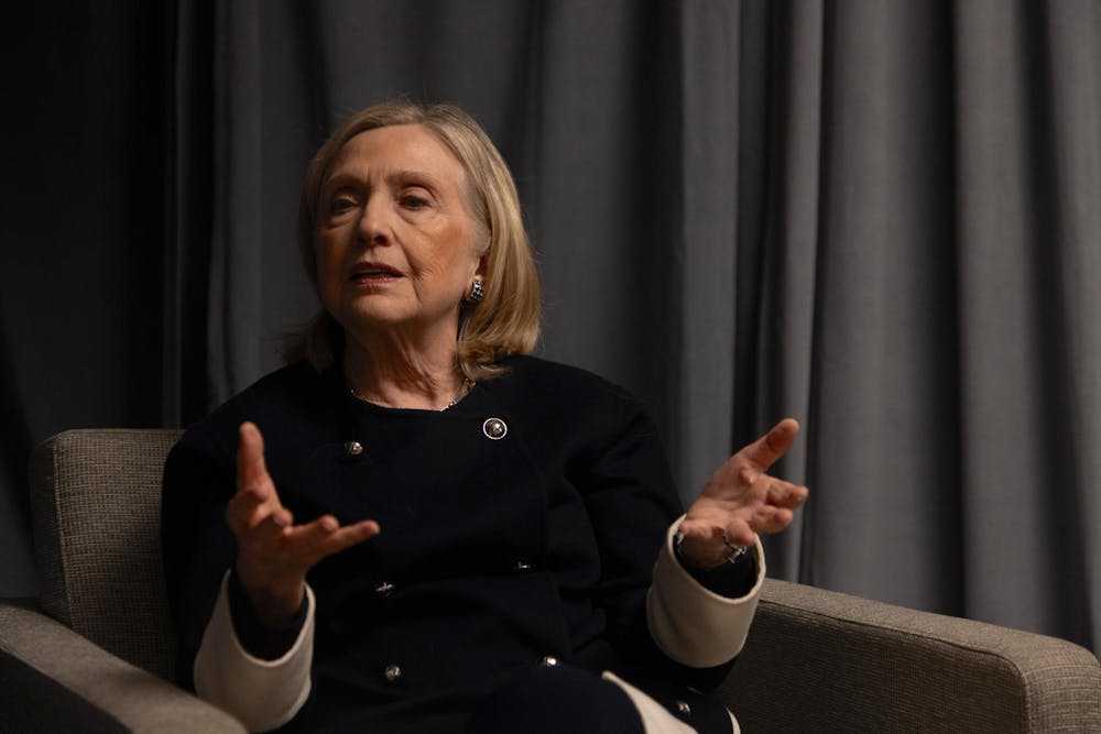 Photo of Hillary Clinton sitting in a grey chair and gesticulating with both hands