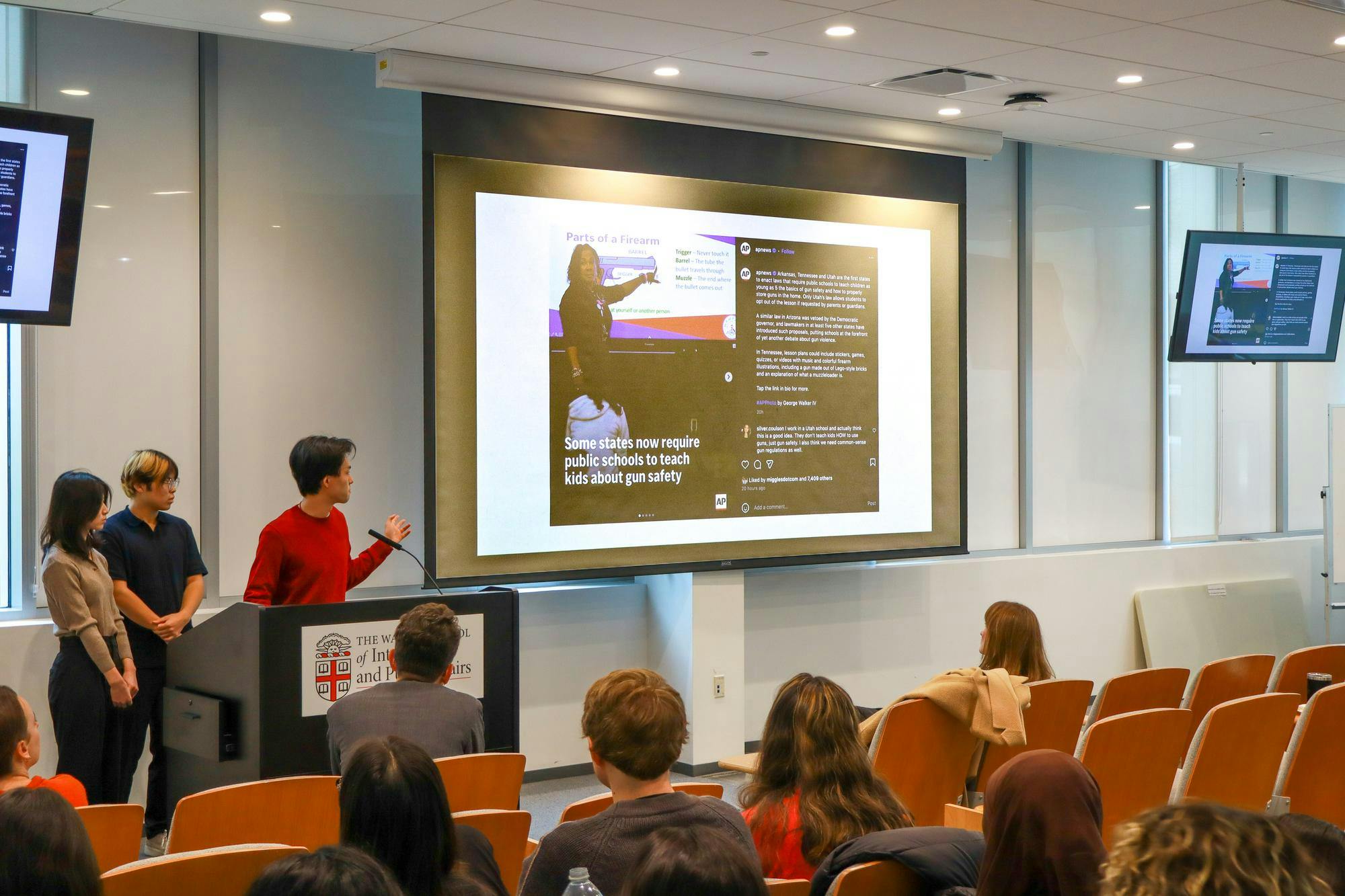 A group of students at the podium is presenting a slide show.