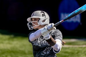 Photo of Brown softball player swinging a bat.
