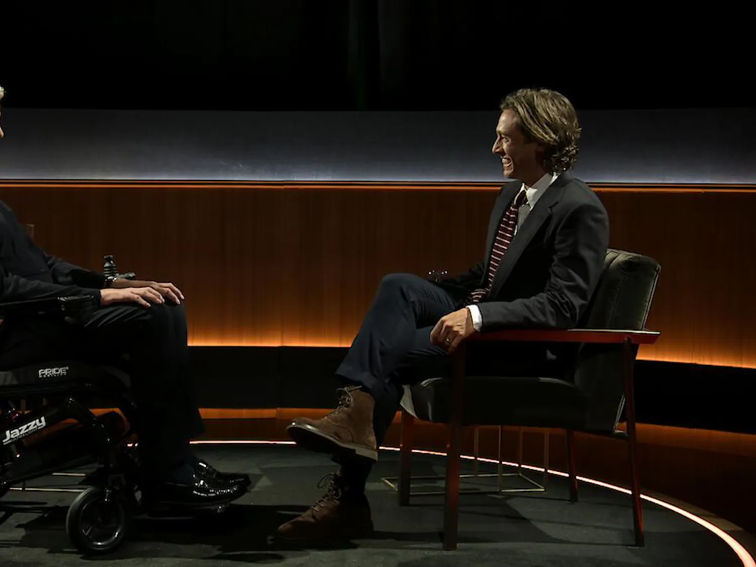 Eric Dane and Brad Falchuk sit across from each other against an illuminated wood background.