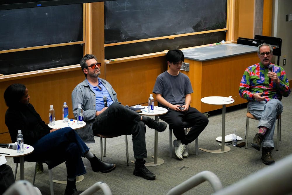 Tamar Nisbett, Jonny Belt, Jack Xu ’27 and Jim Drain sit on chairs in front of a chalkboard. 