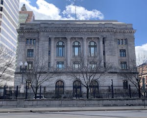 The United States District Court for the District of Rhode Island building with a fence, trees and a road in the foreground.