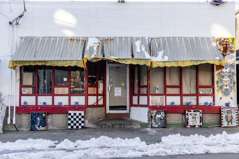 A photo of Louis Family Restaurant, a white building with red framing around the windows and door, and a yellow awning. 