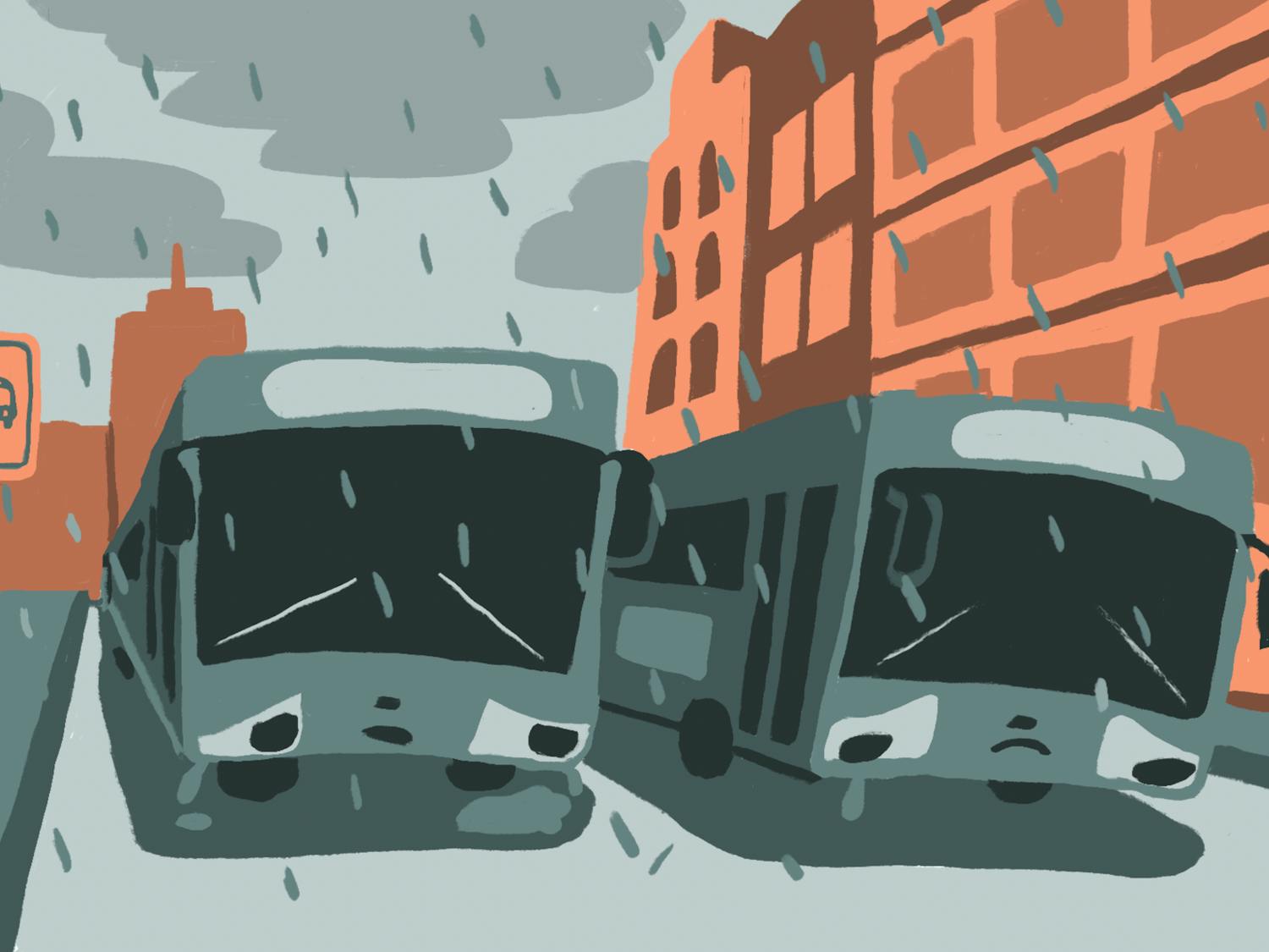 Two gray busses sit in the rain surrounded by orange buildings.
