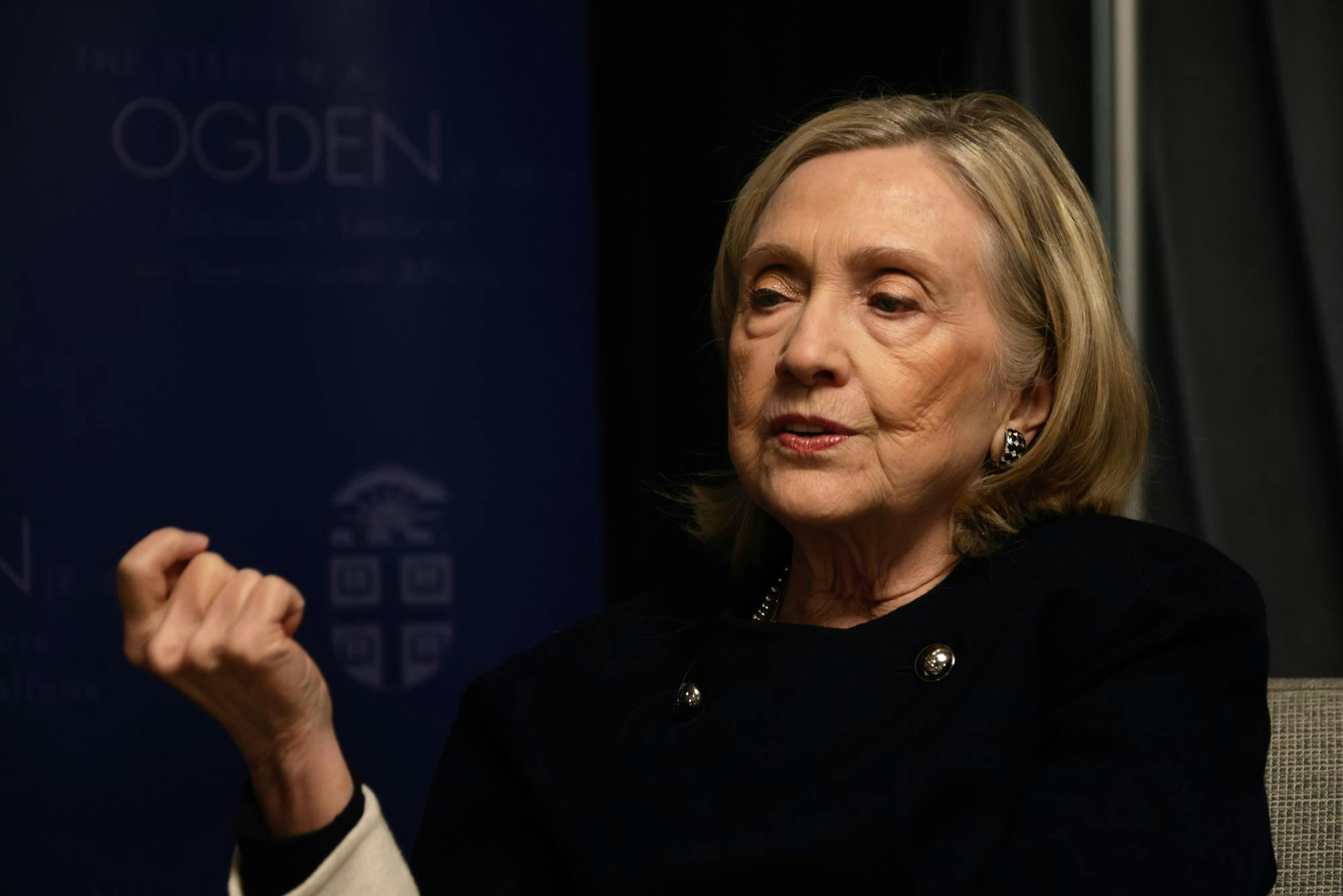 Photo of Hillary Clinton looking to the side and raising her right hand to gesture.