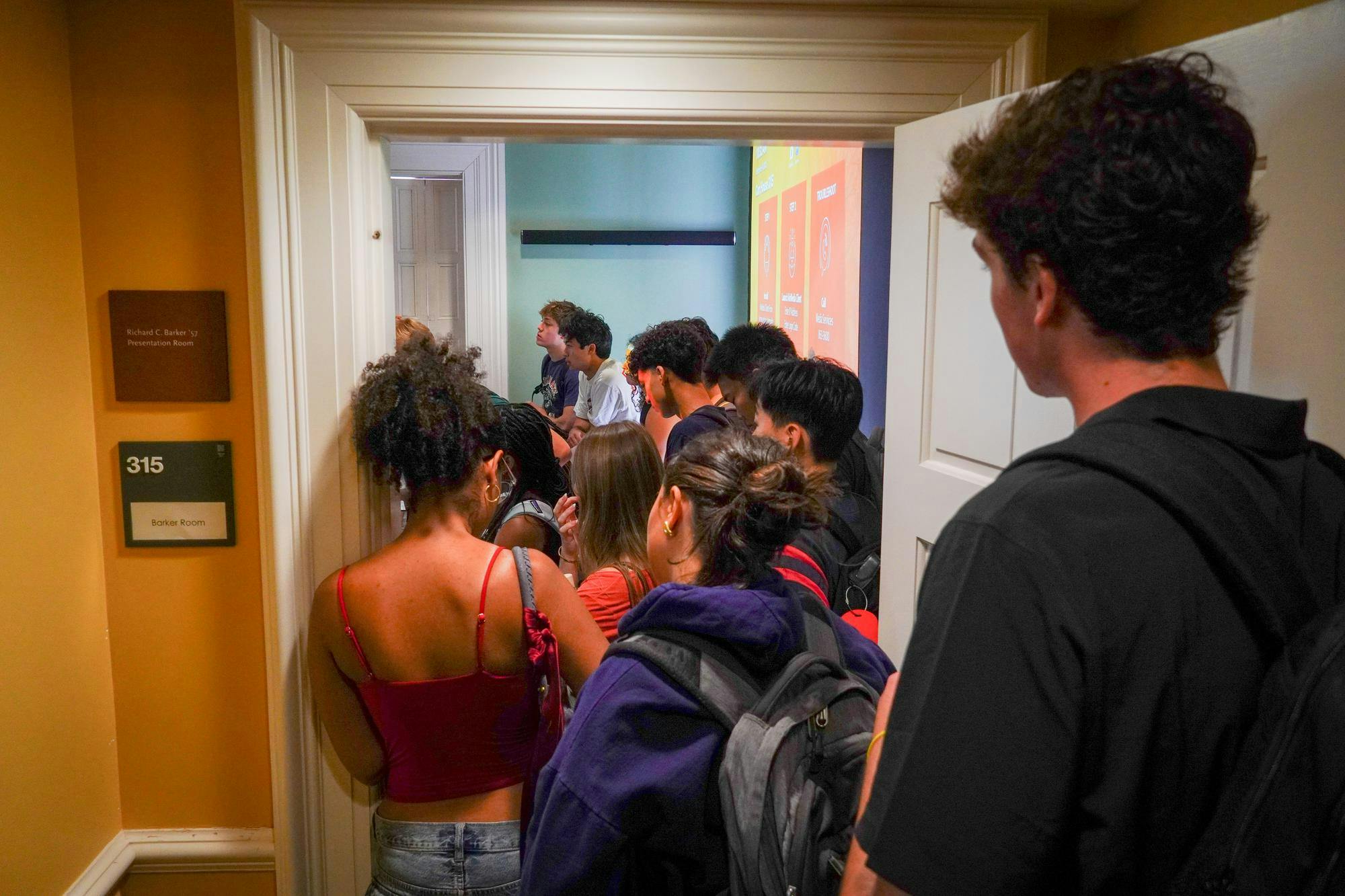 A line of students spill out a doorway. 