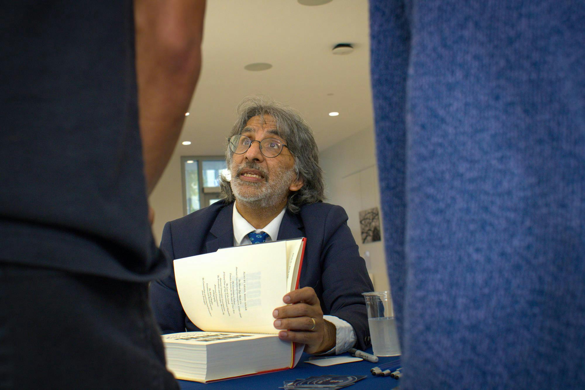 Photo of man at desk holding book open.