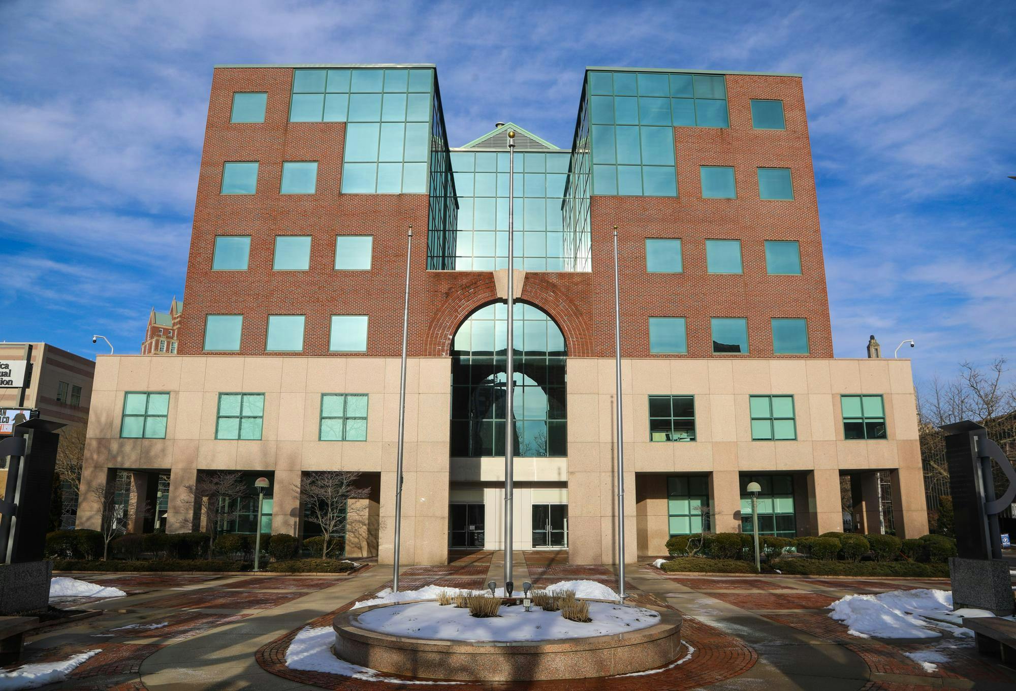 A building with a cream section two floors high at the base with a brick and glass section on top, on a sunny day. 