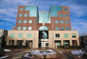 A building with a cream section two floors high at the base with a brick and glass section on top, on a sunny day. 