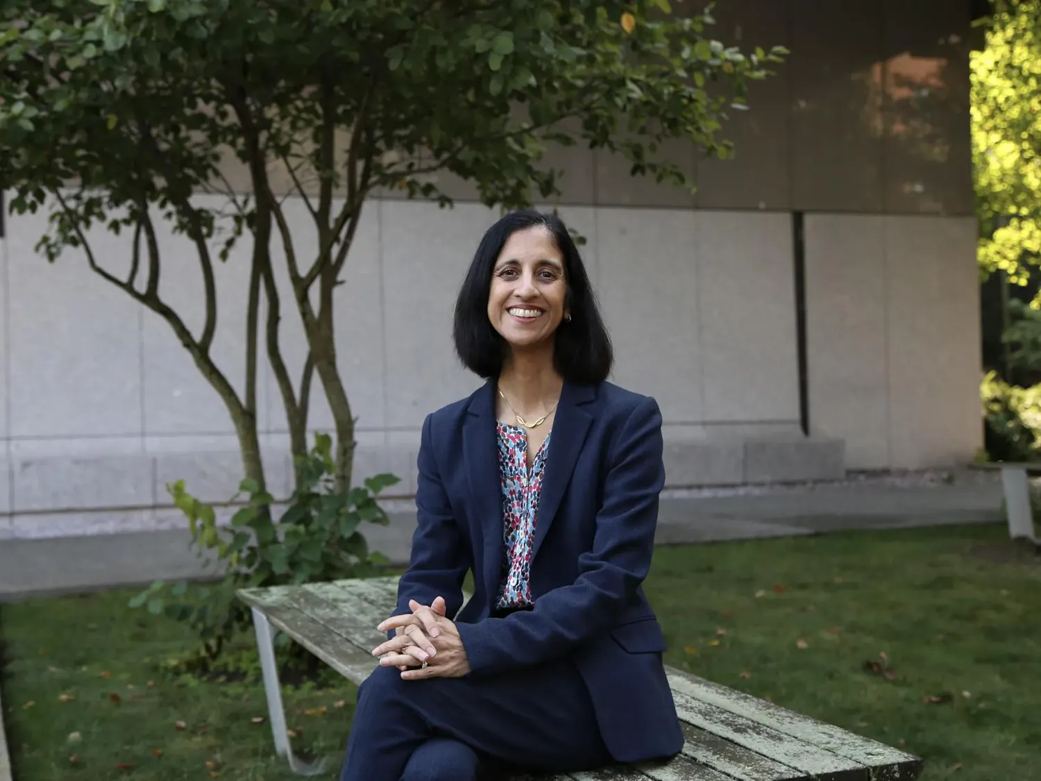 A portrait of Tejal Desai sitting on a bench.