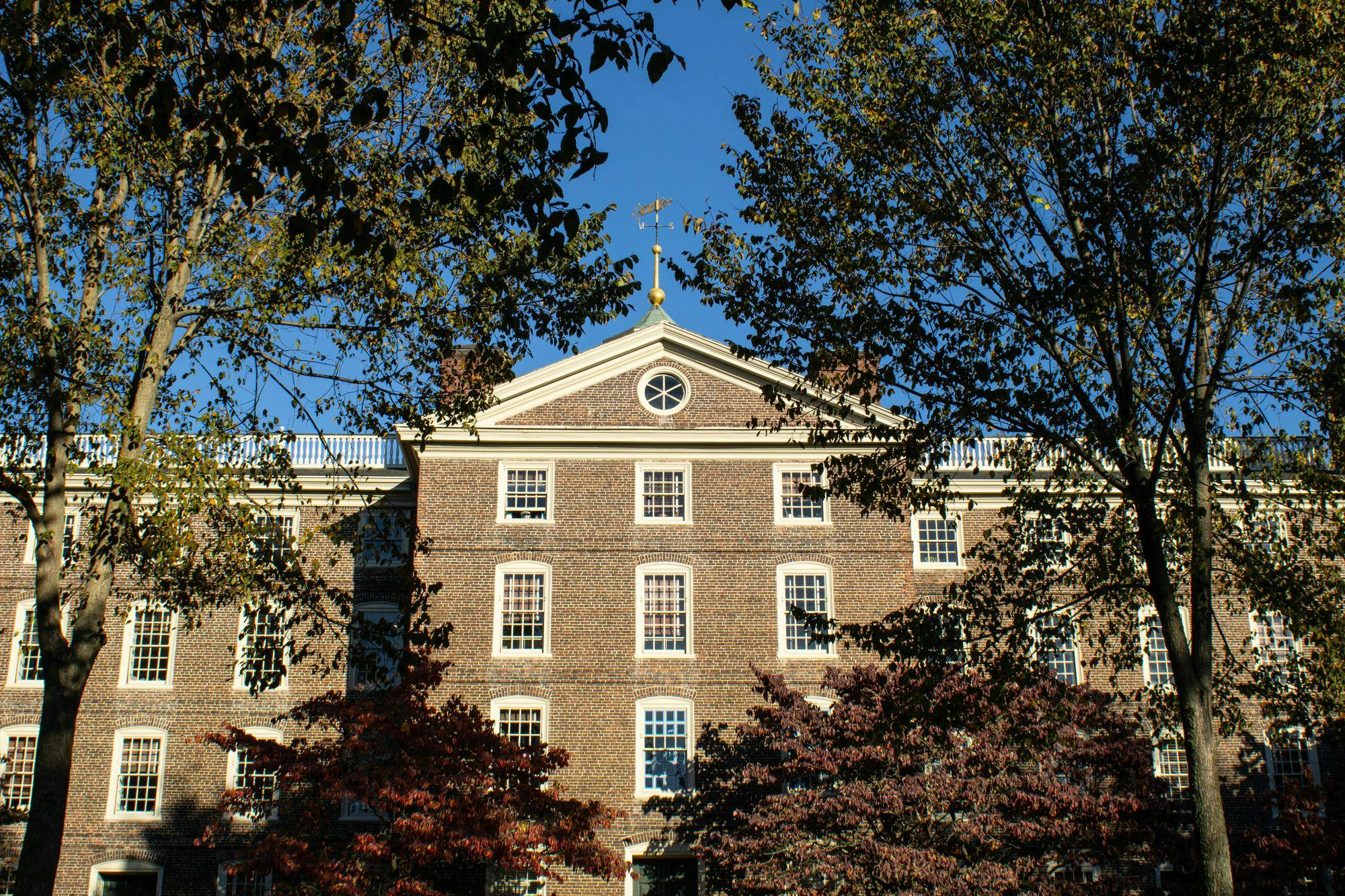 A photo of University Hall with multi-colored fall trees surrounding it.