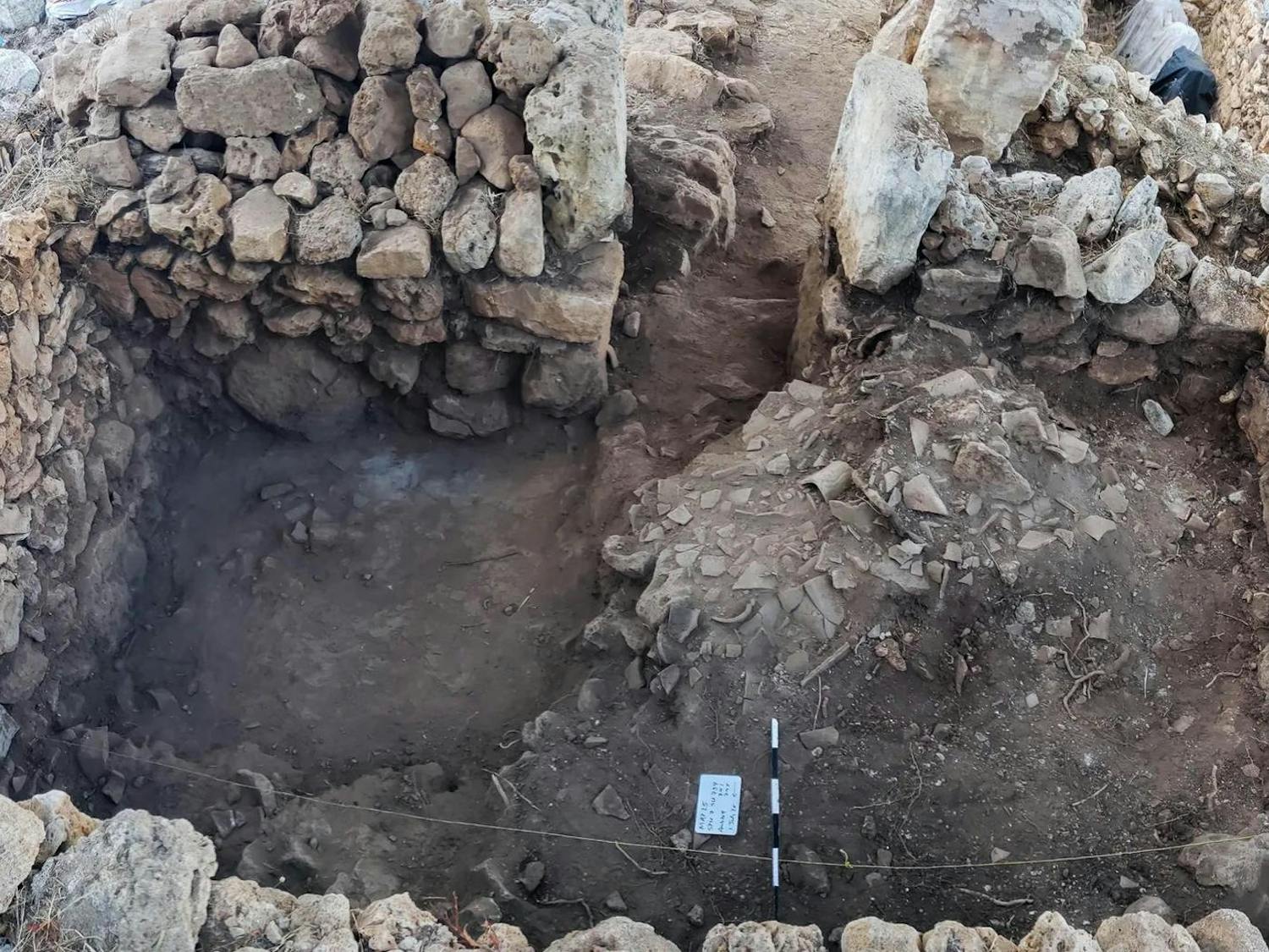 Photo of the archeological site, with rocks surrounding the cleared-out space.