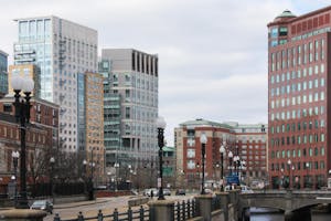 A Providence, Rhode Island skyline featuring multiple lampposts and tall buildings with glass windows and a cloudy sky.